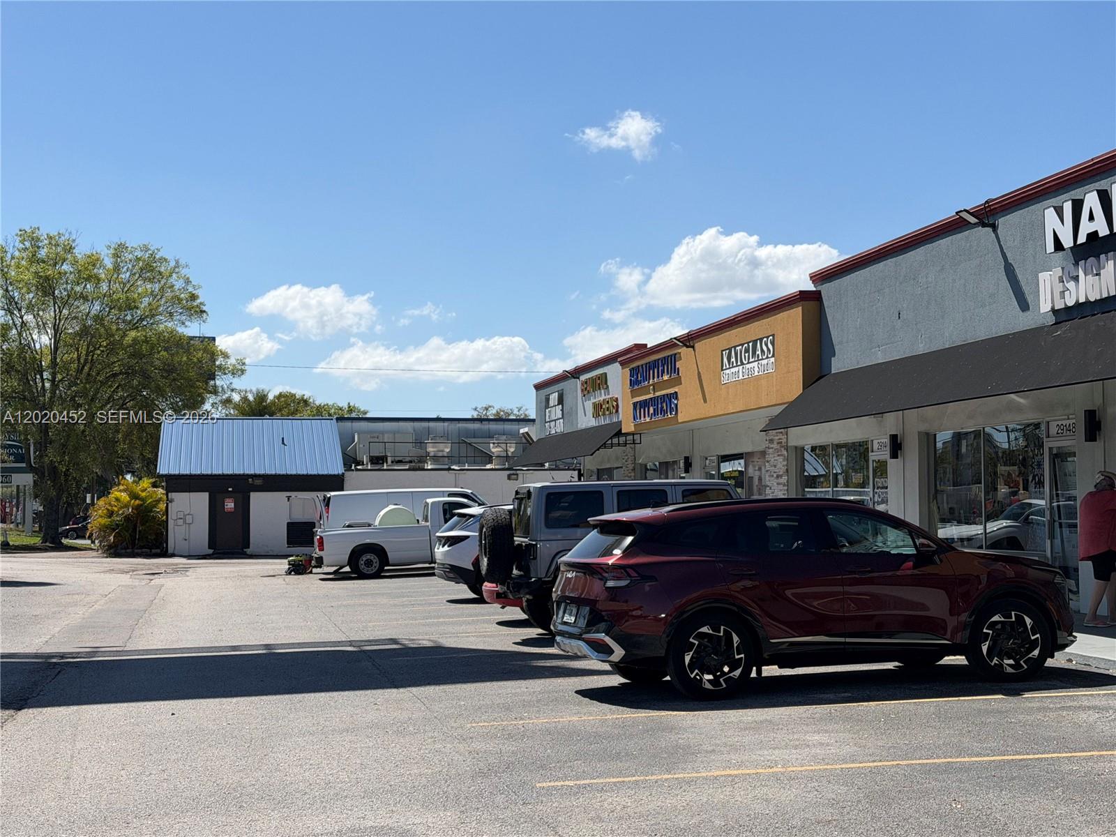 A parking lot sits in front of a row of commercial storefronts under a blue sky — 29168 N US HWY 19, Clearwater FL 33761, CLEARWATER, FL