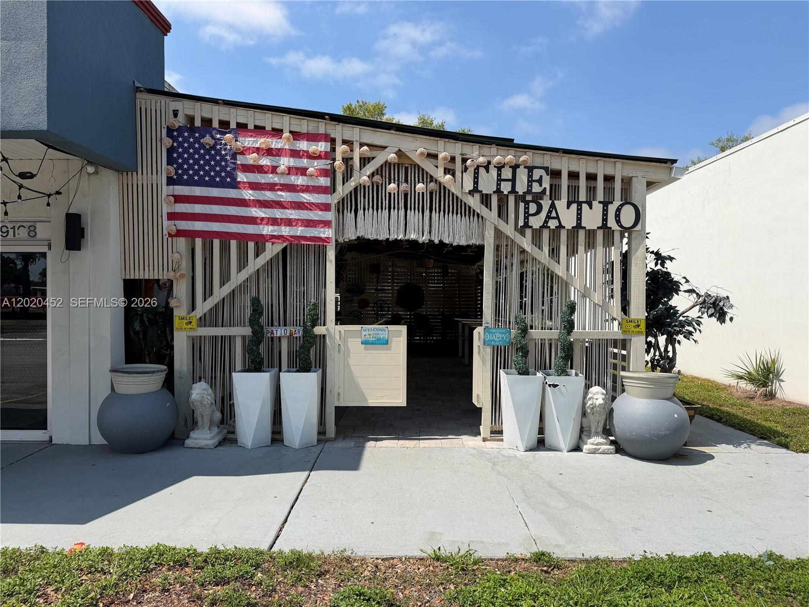 The exterior of a commercial patio space features a wooden lattice facade and American flag — 29168 N US HWY 19, Clearwater FL 33761, CLEARWATER, FL