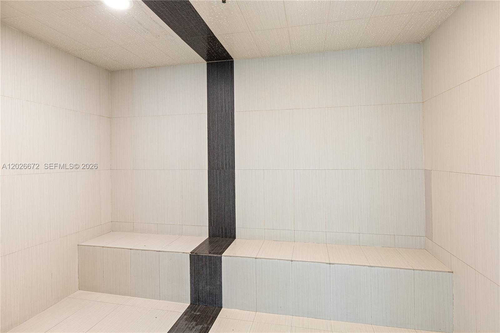 This is a tiled steam room featuring built-in benches and a dark accent stripe — 951 Brickell Ave # 1801, Miami FL 33131, MIAMI, FL