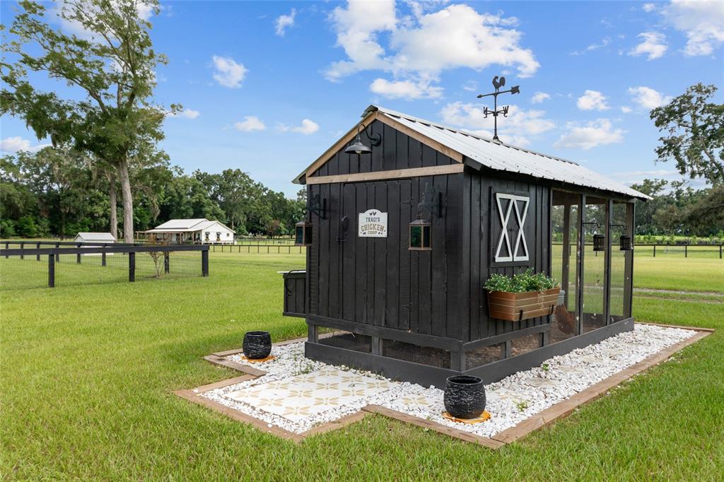 A black wooden chicken coop with a metal roof sits on a gravel patio — 2152 NE 120TH PLACE, ANTHONY, FL