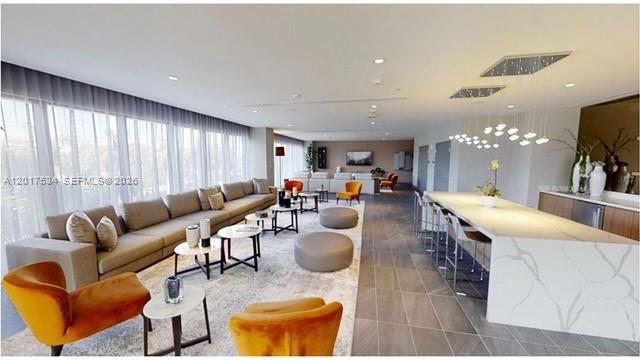 A modern, open-concept living room features a long sofa, orange armchairs, and a kitchen island — 5350 NW 84th Ave # 1613, Doral FL 33166, DORAL, FL