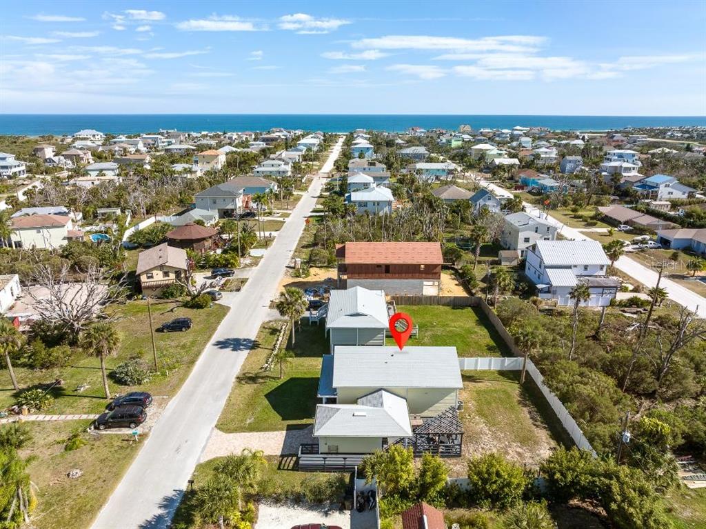 An aerial view shows a light-colored house with a metal roof near the ocean — 8 MOODY DRIVE, PALM COAST, FL