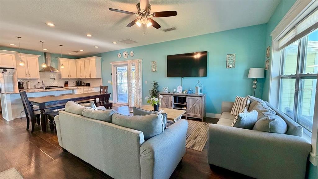 An open-concept living room and kitchen feature light blue walls, wood flooring, and a ceiling fan — 8 MOODY DRIVE, PALM COAST, FL