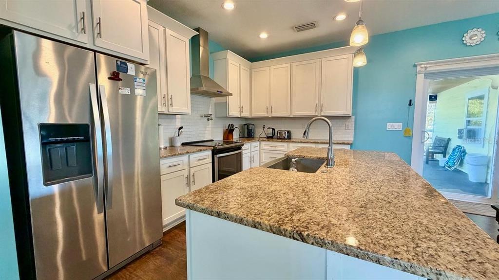 A kitchen with white cabinets, granite countertops, stainless steel appliances, and light blue walls — 8 MOODY DRIVE, PALM COAST, FL