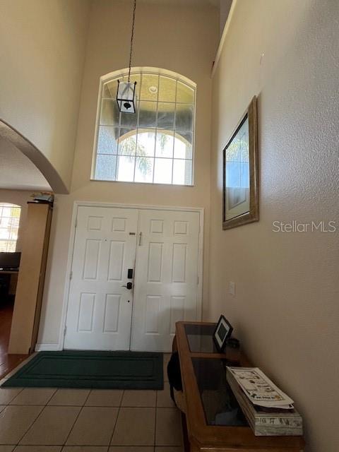 A high-ceilinged entryway features a double door, a large arched window, and tile flooring — 806 LOST GROVE CIRCLE, WINTER GARDEN, FL