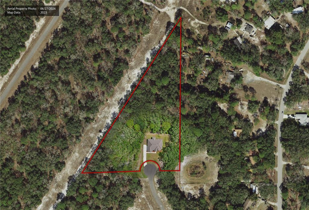 An aerial view shows a house situated on a large, triangular-shaped wooded lot — 17000 NOKOTA AVENUE, HUDSON, FL