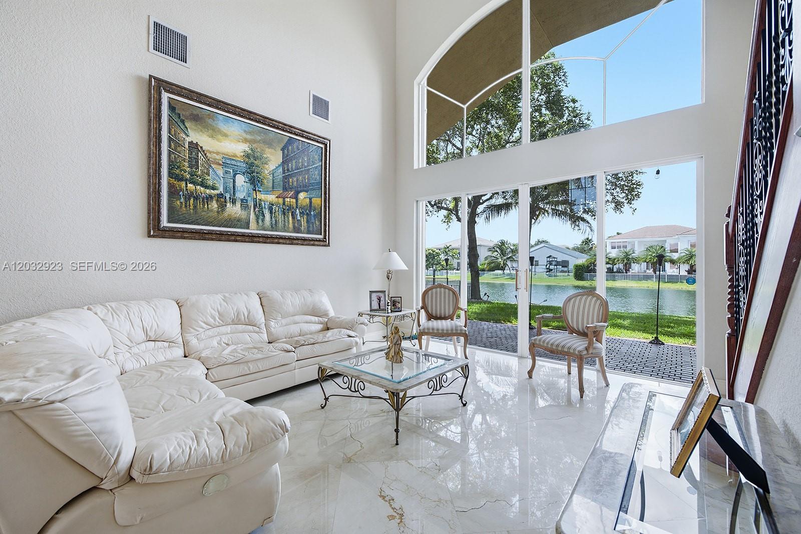 A bright living room features a white sectional sofa, marble floors, and large floor-to-ceiling windows — 18543 SW 49th St, Miramar FL 33029, MIRAMAR, FL
