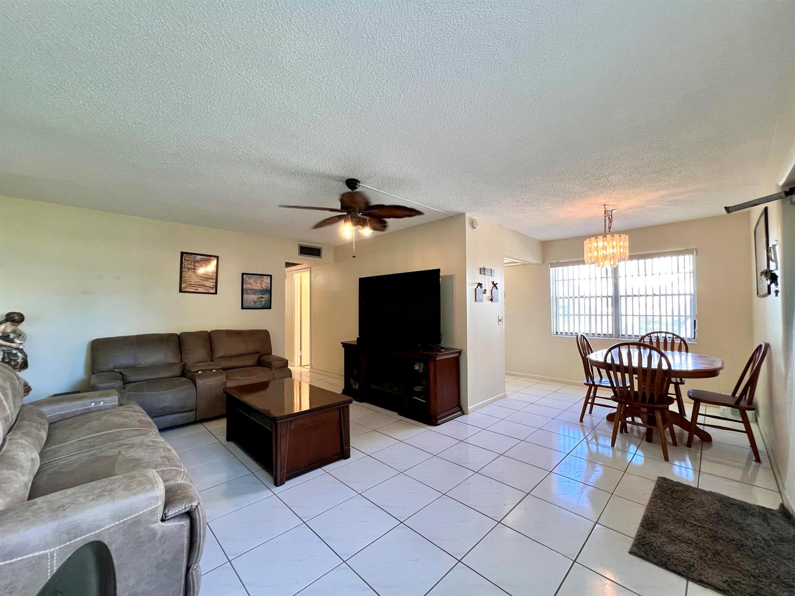 A living room and dining area with tile flooring, a ceiling fan, and wooden furniture — 76 Sheffield D, West Palm Beach FL 33417, WEST PALM BEACH, FL