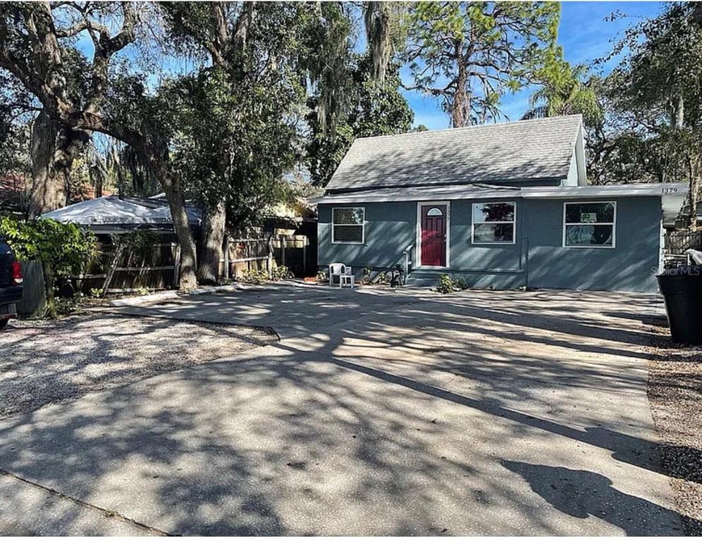 A single-story house with a gray exterior, red front door, and a large concrete driveway — 1379 S MARTIN LUTHER KING JR AVENUE, CLEARWATER, FL