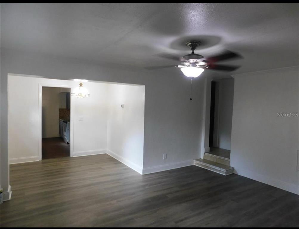 An interior view shows a living room with wood-look flooring, a ceiling fan, and steps — 1379 S MARTIN LUTHER KING JR AVENUE, CLEARWATER, FL