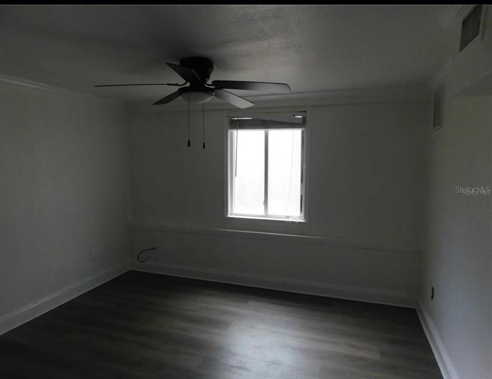 An empty bedroom features white walls, a ceiling fan, a window, and wood-look flooring — 1379 S MARTIN LUTHER KING JR AVENUE, CLEARWATER, FL