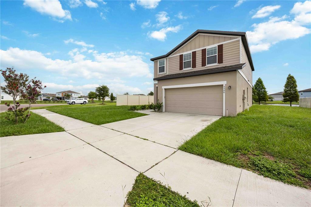 A two-story house with a beige stucco exterior and a two-car garage — 5506 TURKEY CREEK WAY, LAKELAND, FL