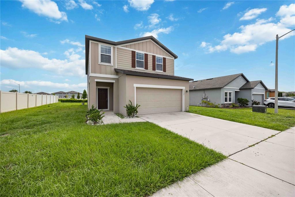 A two-story suburban house with a tan stucco exterior, brown shutters, and a two-car garage — 5506 TURKEY CREEK WAY, LAKELAND, FL