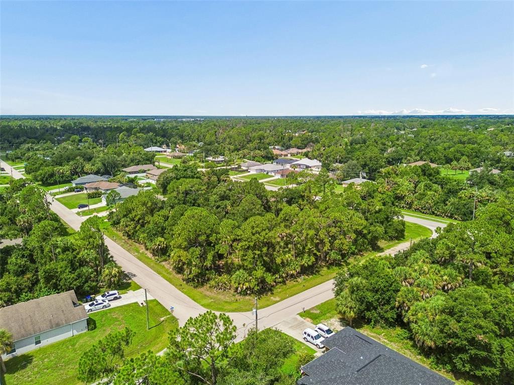 An aerial view shows a vacant, tree-covered residential lot situated at a street intersection — 15 HEATHER TERRACE, NORTH PORT, FL