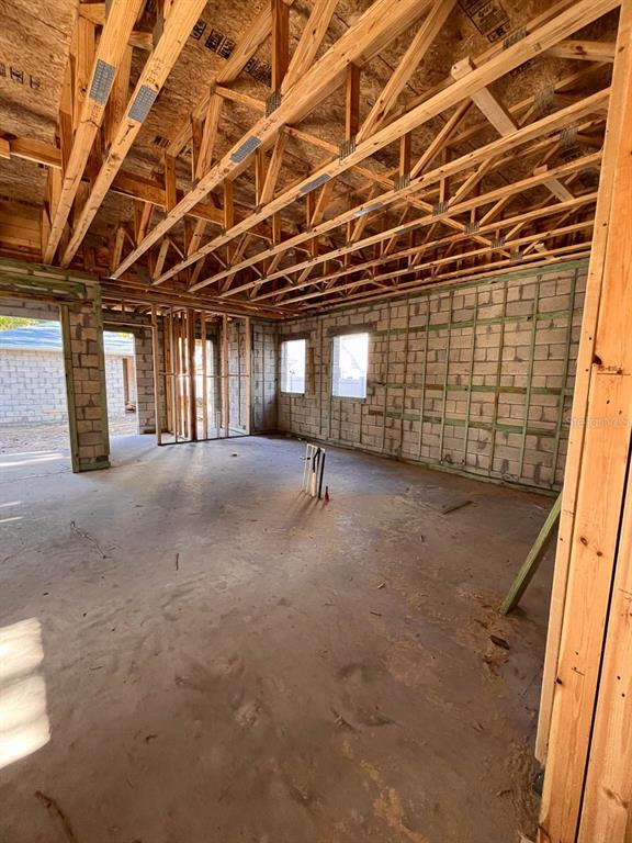 An unfinished room with concrete block walls, exposed wood roof trusses, and a concrete floor — 485 11TH AVENUE N, ST PETERSBURG, FL