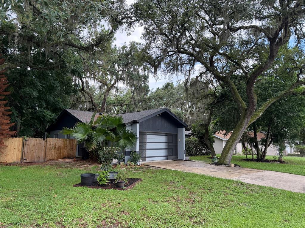 A single-story house with a gray exterior, a garage, and large oak trees in front — 113 WINDING RIDGE DRIVE, SANFORD, FL
