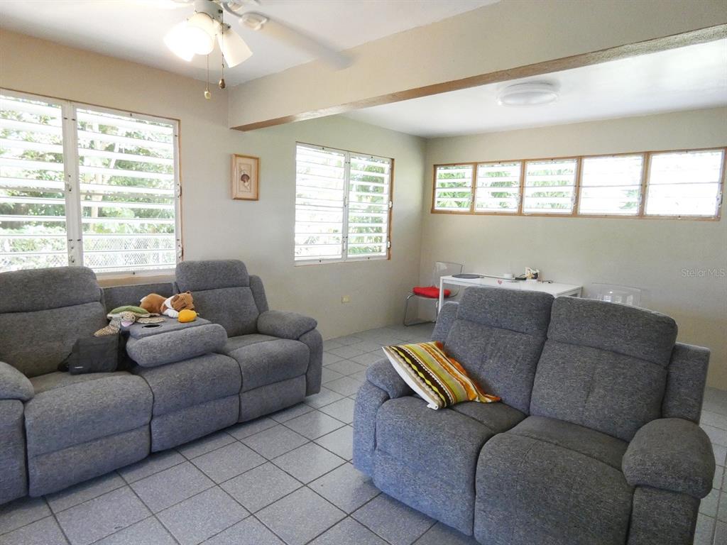 A living room features gray sofas, tiled floors, and multiple louvered windows — 37 CALLE CORAL, VIEQUES, PR
