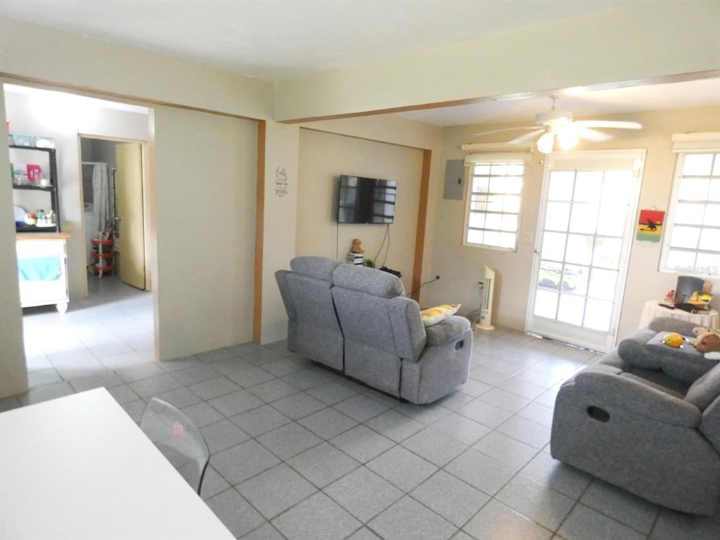 A living room with gray tile floors, two gray sofas, and a wall-mounted television — 37 CALLE CORAL, VIEQUES, PR