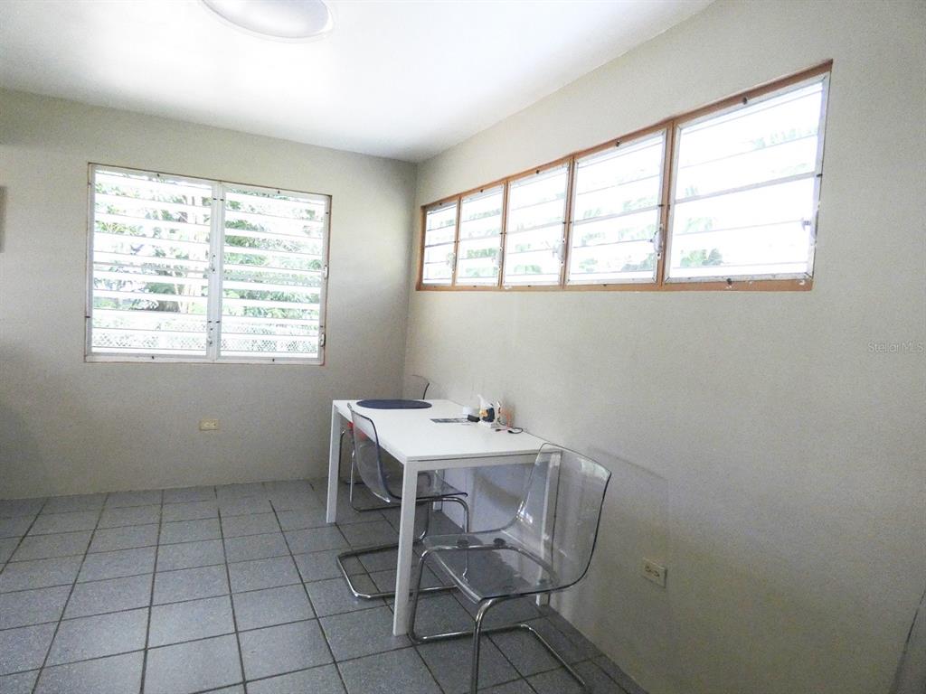 A room with tile flooring, a white table, two clear chairs, and louvered windows — 37 CALLE CORAL, VIEQUES, PR