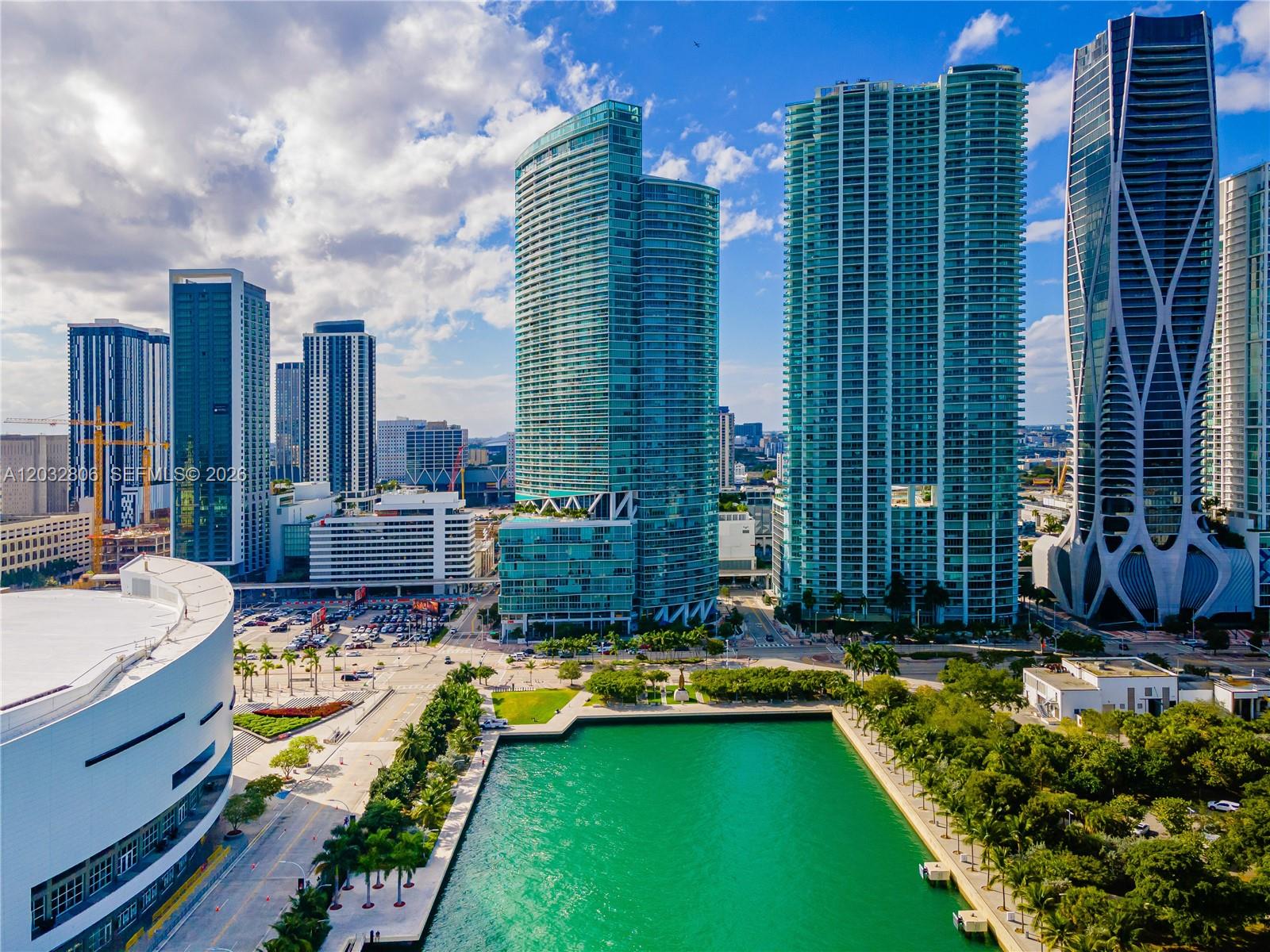 An aerial view shows a city skyline with tall glass skyscrapers overlooking a waterfront park — 888 Biscayne Blvd # 4011, Miami FL 33132, MIAMI, FL