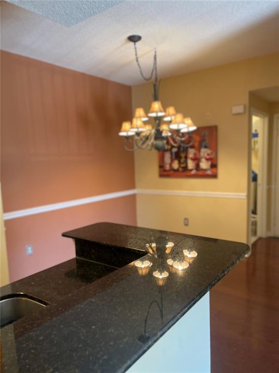 A kitchen island with a dark granite countertop sits beneath a multi-light chandelier — 2001 TIZEWELL CIRCLE UNIT 1504, ORLANDO, FL