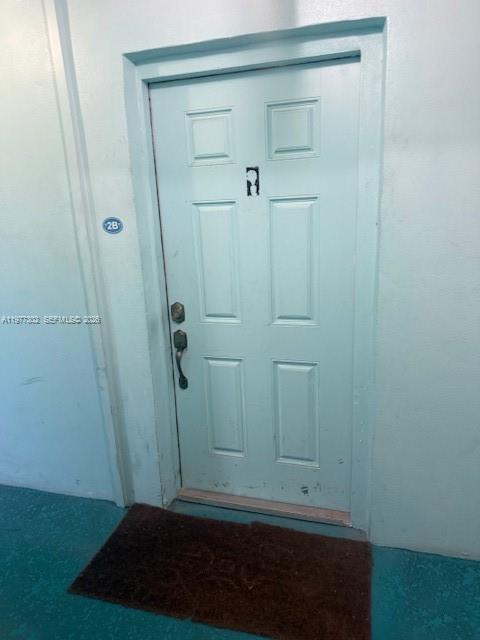 A light blue six-panel door with a dark doormat sits in a plain hallway — 701 Collins Ave # 2B, Miami Beach FL 33139, MIAMI BEACH, FL
