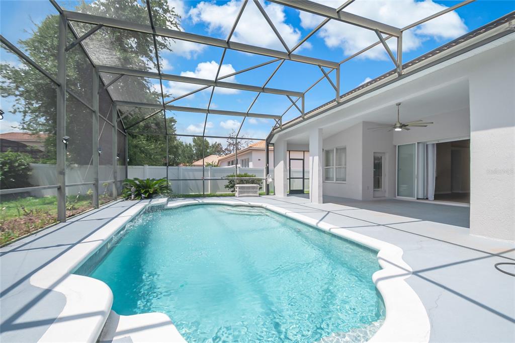 A screened-in patio features a swimming pool with a water feature and a ceiling fan — 1363 GLENWICK DRIVE, WINDERMERE, FL