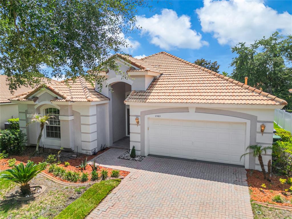 A single-story house with a tiled roof, a two-car garage, and a brick paver driveway — 1363 GLENWICK DRIVE, WINDERMERE, FL