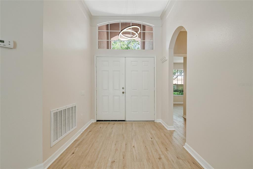 A bright entryway features light wood-look flooring, double front doors, and an arched transom window — 1363 GLENWICK DRIVE, WINDERMERE, FL