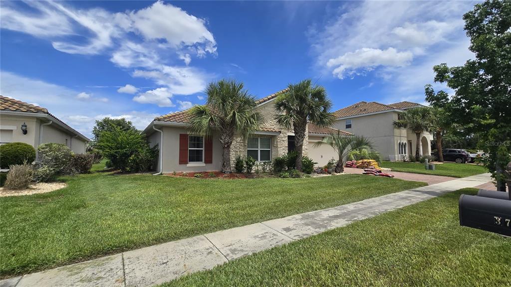 A single-story house with a tan exterior, stone accents, and palm trees in the front yard — 3729 ISLES ARBOR LANE, KISSIMMEE, FL