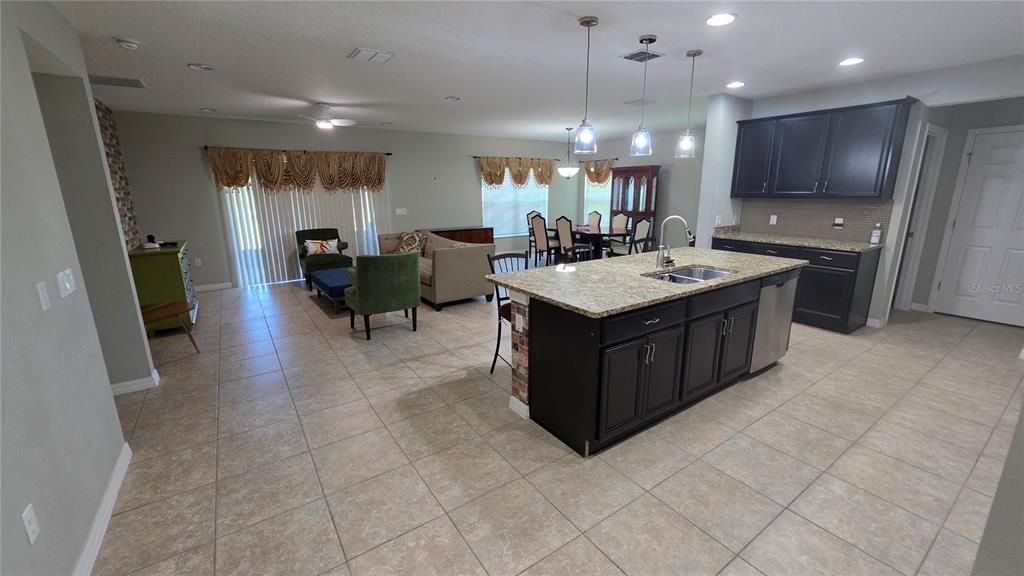 An open-concept kitchen with a granite island and dark cabinets overlooks a living area — 3729 ISLES ARBOR LANE, KISSIMMEE, FL