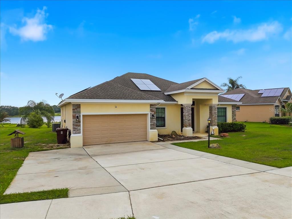A single-story house with a tan stucco exterior, stone accents, and a two-car garage — 4387 DINNER LAKE BOULEVARD, LAKE WALES, FL