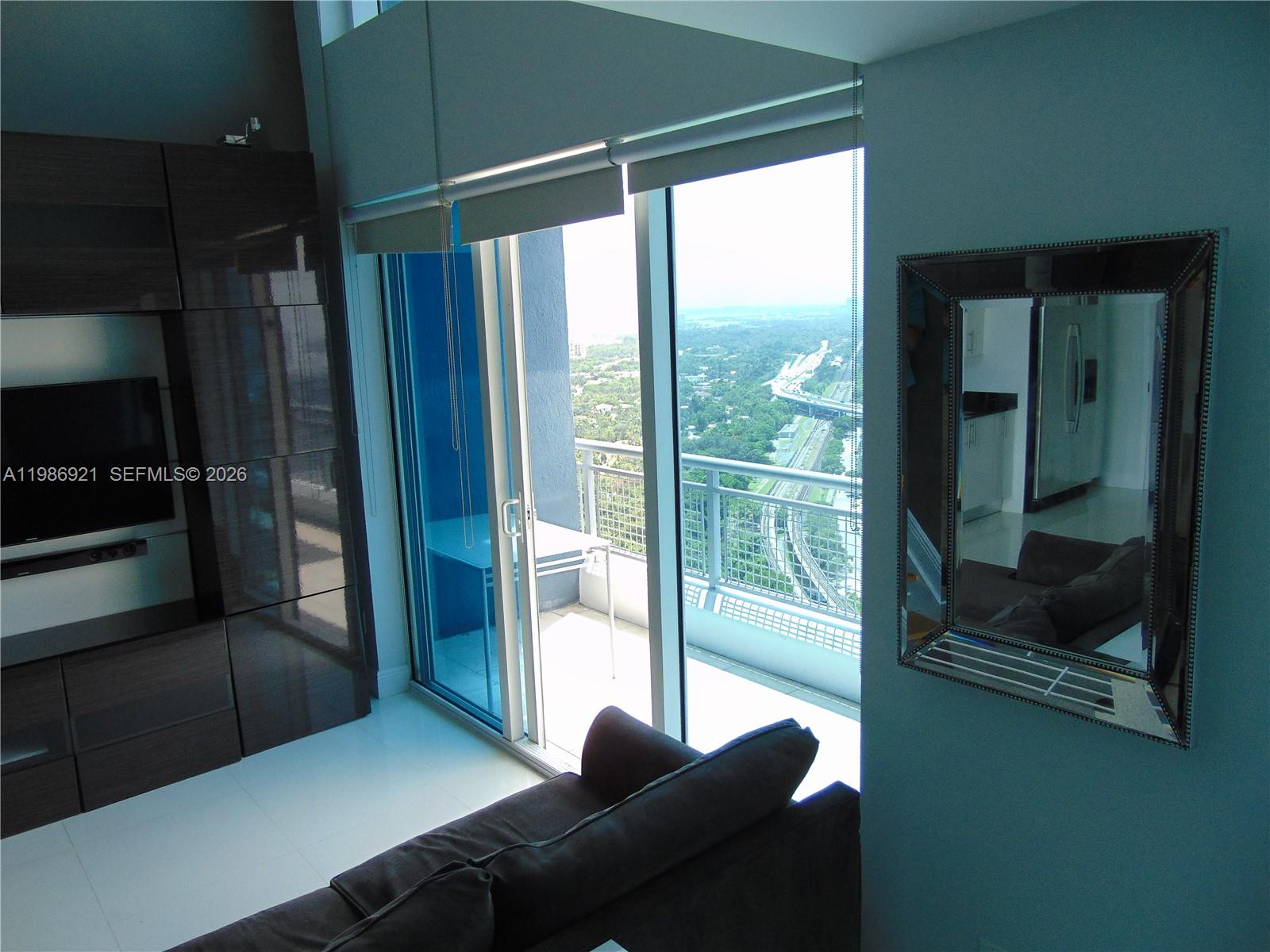 A living room features dark cabinetry, a sofa, and a balcony overlooking a highway — 60 SW 13th St # 2619, Miami FL 33130, MIAMI, FL