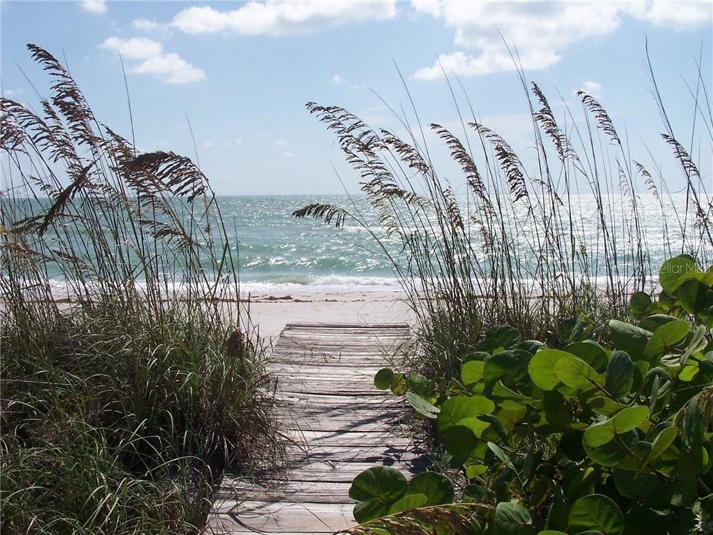 A wooden boardwalk leads through sea oats and greenery toward the ocean beach — 9400 LITTLE GASPARILLA ISLAND UNIT H8, PLACIDA, FL