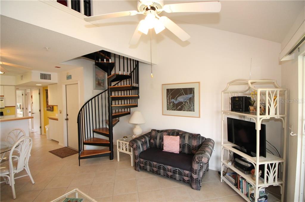 A living room features a spiral staircase, tile flooring, a patterned sofa, and a ceiling fan — 9400 LITTLE GASPARILLA ISLAND UNIT H8, PLACIDA, FL