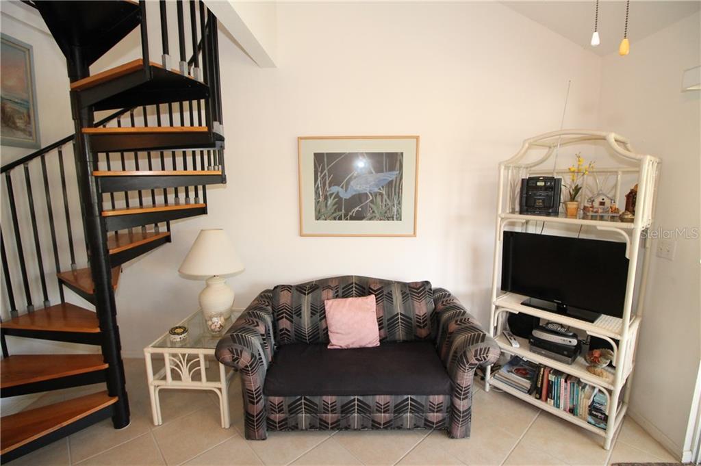 A living room features a spiral staircase, a patterned loveseat, and a white wicker shelving unit — 9400 LITTLE GASPARILLA ISLAND UNIT H8, PLACIDA, FL