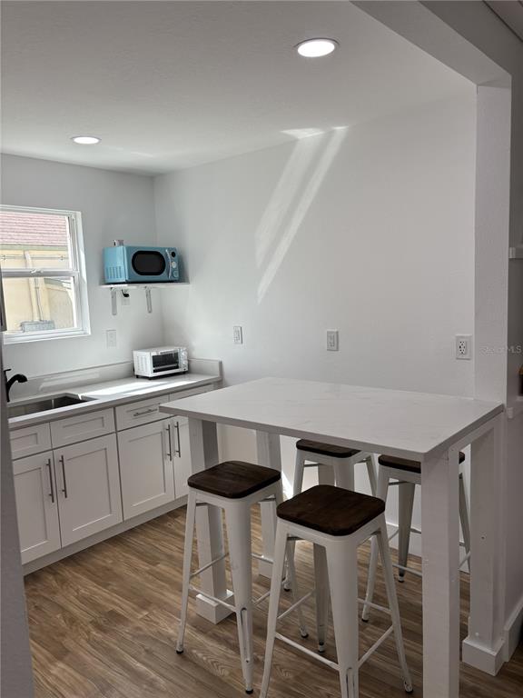 A small kitchen features white cabinets, a light-colored countertop, and a high-top table with stools — 14141 GULF BOULEVARD UNIT 5, MADEIRA BEACH, FL