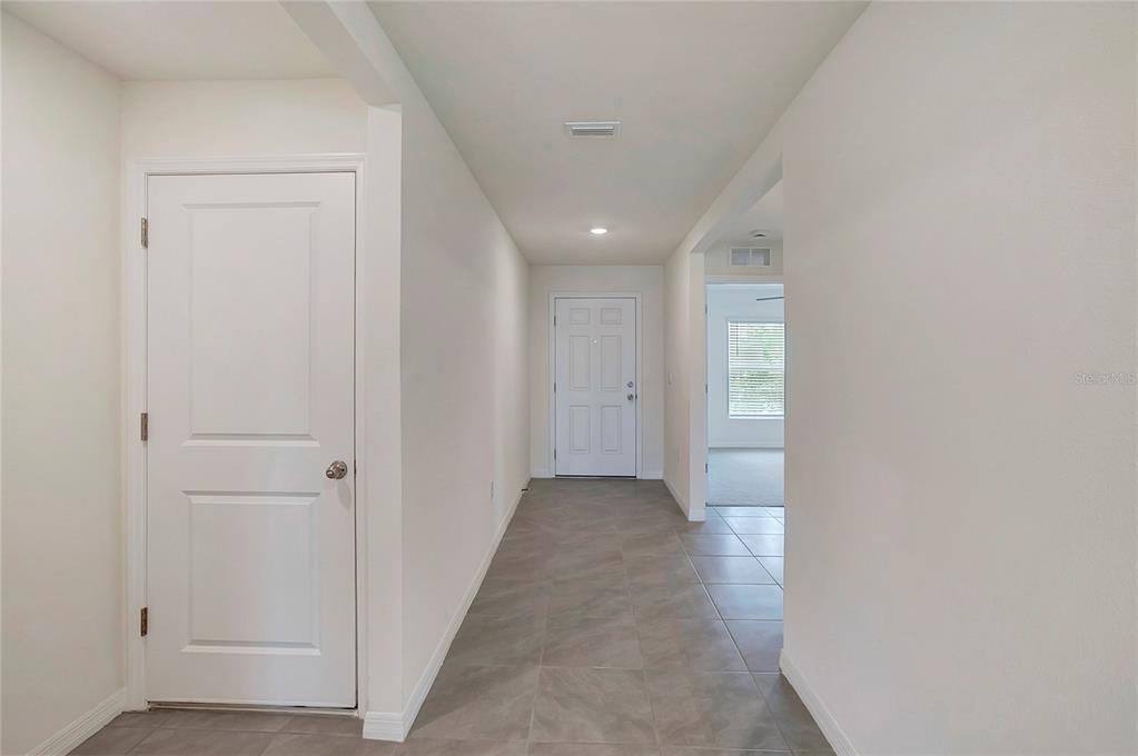 A hallway with gray tile flooring leads to a white front door — 810 ACE OUTLAW AVENUE, RUSKIN, FL