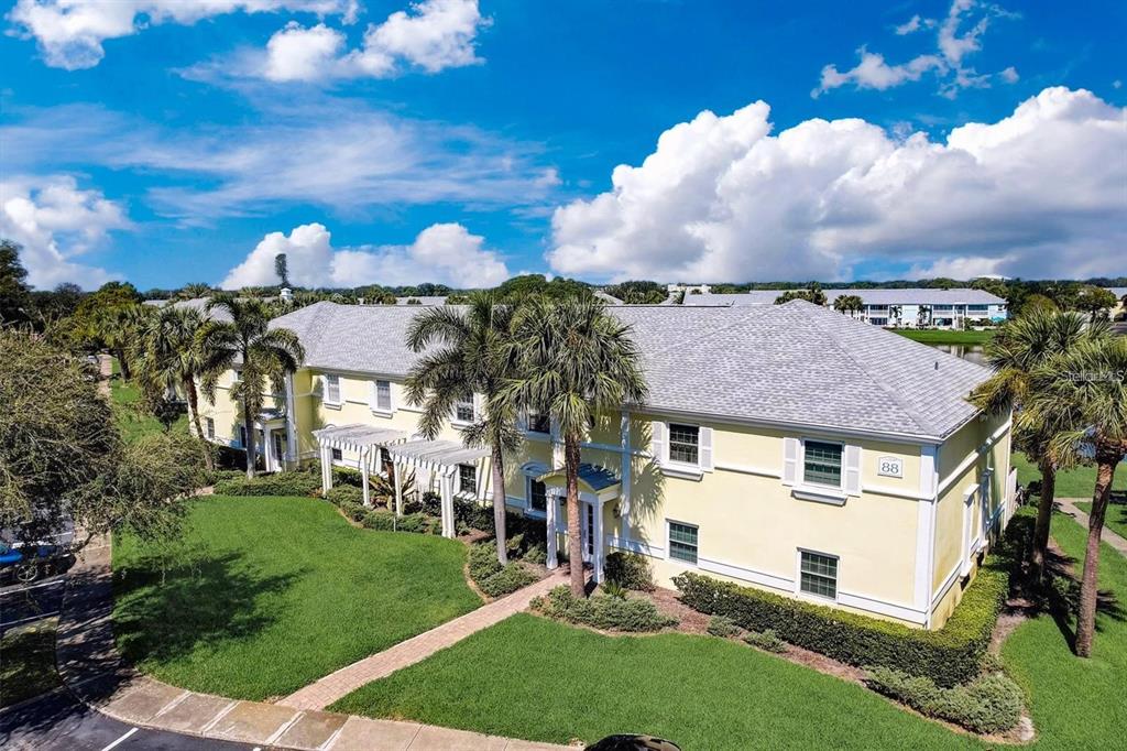 An exterior view of a two-story yellow apartment building with palm trees and a lawn — 121 SEAHORSE DRIVE SE UNIT C, ST PETERSBURG, FL