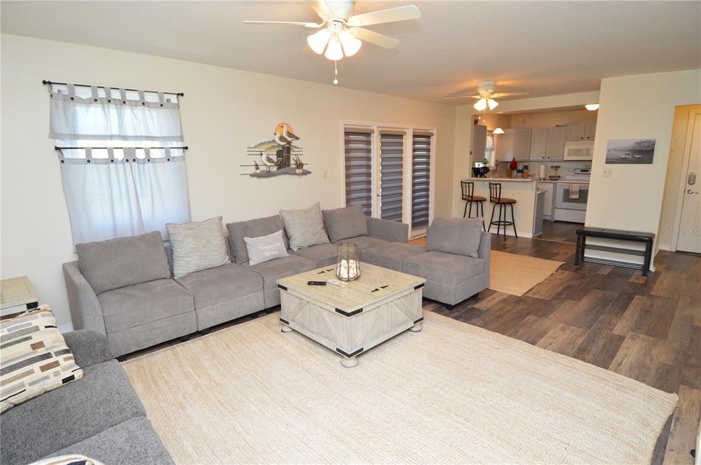 A living room with a gray sectional sofa, coffee table, and an open kitchen area — 121 SEAHORSE DRIVE SE UNIT C, ST PETERSBURG, FL