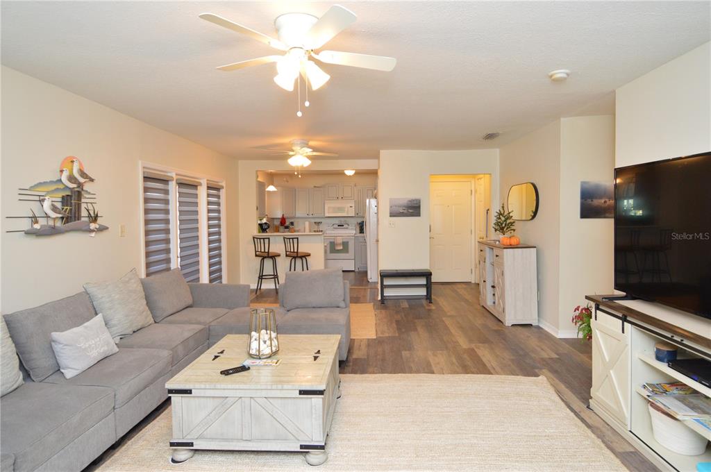 A living room with gray sectional seating, a coffee table, and an open kitchen area — 121 SEAHORSE DRIVE SE UNIT C, ST PETERSBURG, FL