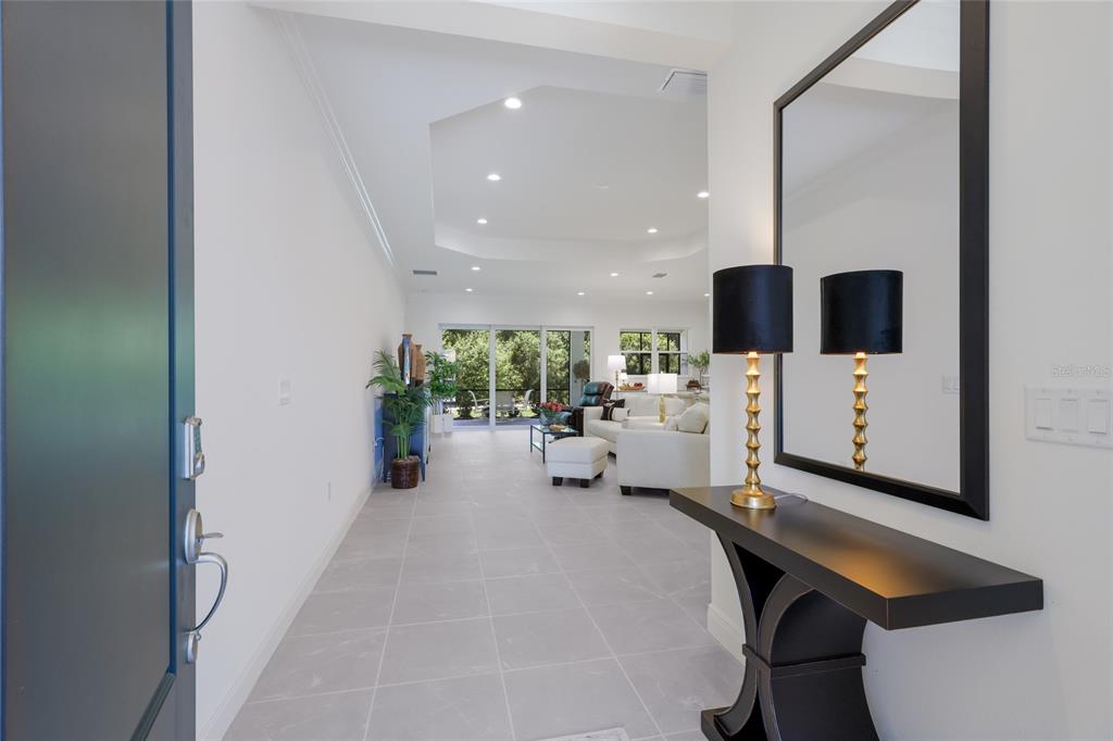 A bright entryway features light tile flooring, a console table with lamps, and a mirror — 2493 PARADISE PLUM DRIVE, SARASOTA, FL