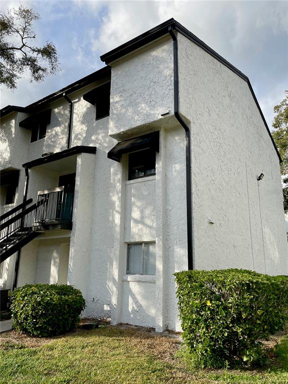 A two-story white stucco building features black trim, a metal staircase, and landscaped bushes — 4263 S SEMORAN BOULEVARD UNIT 9, ORLANDO, FL
