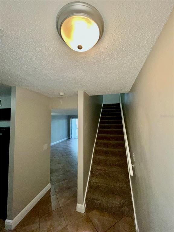 An interior view shows a tiled entryway, a carpeted staircase, and a view into a living area — 4263 S SEMORAN BOULEVARD UNIT 9, ORLANDO, FL