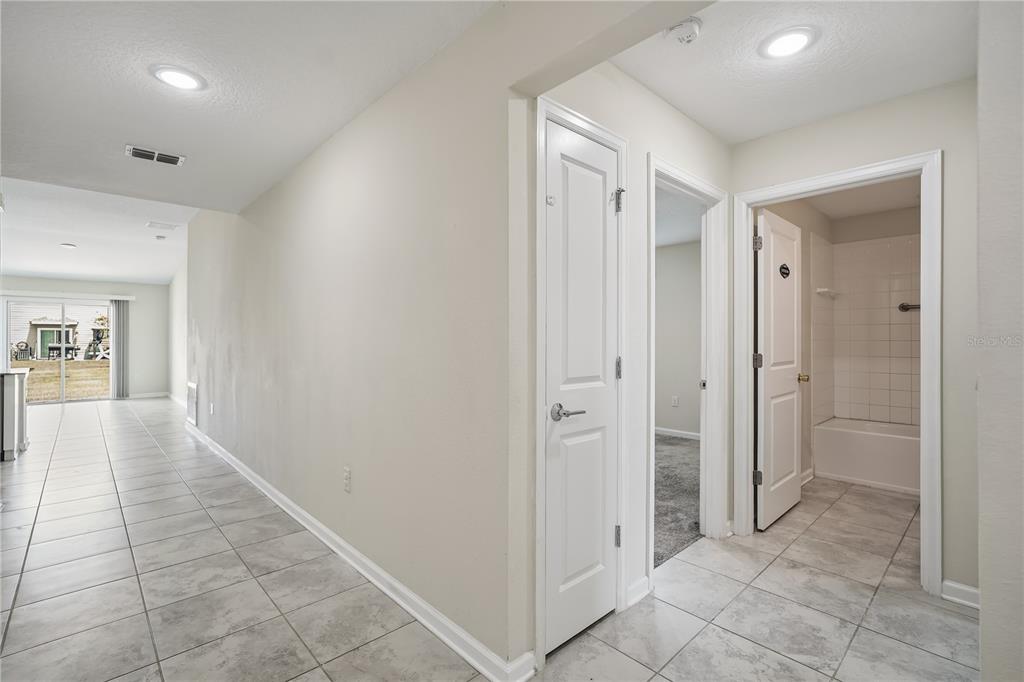 A hallway with tile flooring leads to a living area, a bedroom, and a bathroom — 4409 BLACKBIRD STREET, KISSIMMEE, FL