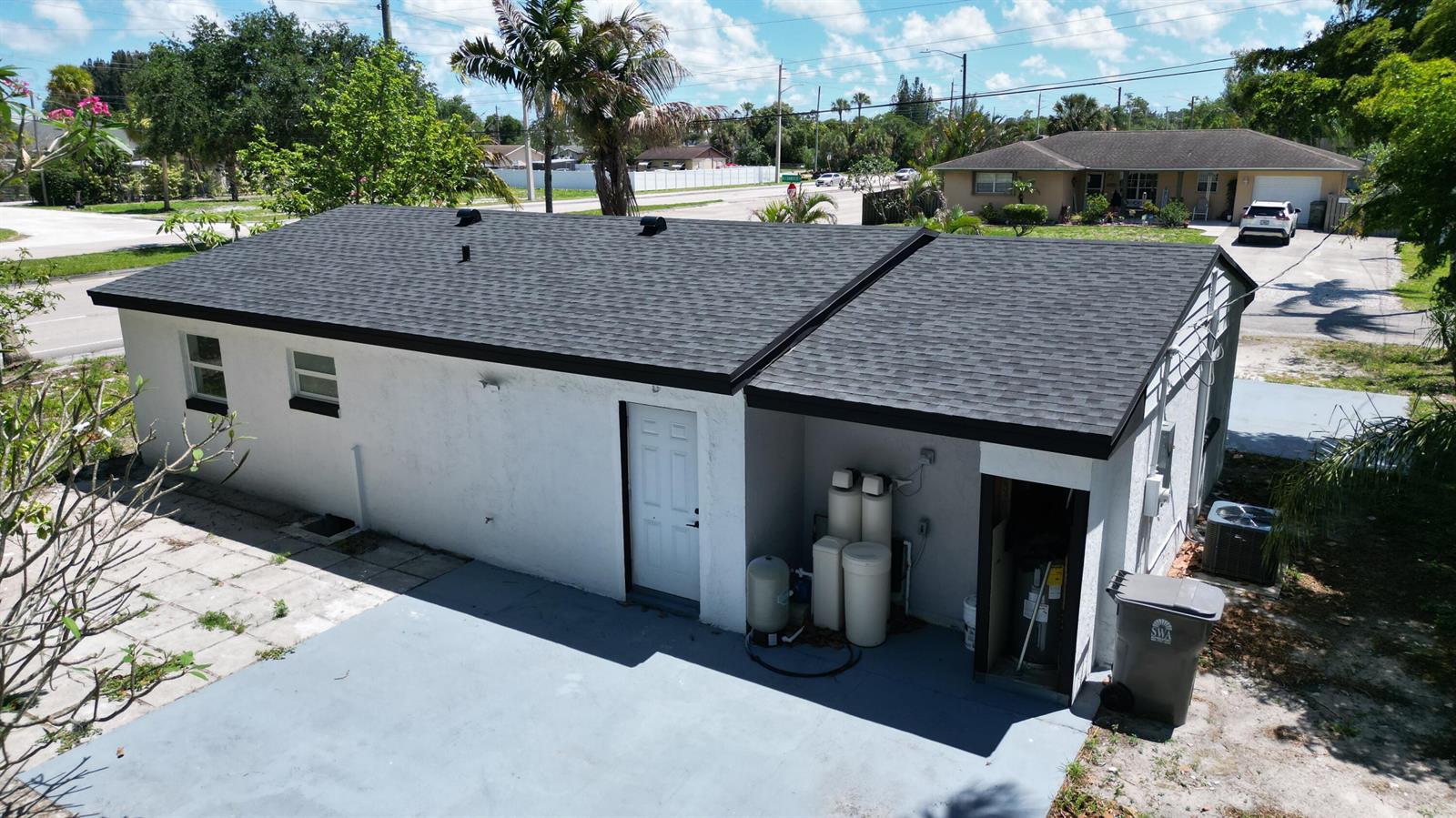 An aerial view shows the exterior of a white house with a new dark shingle roof — 6507 Alexander Road, West Palm Beach FL 33413, WEST PALM BEACH, FL