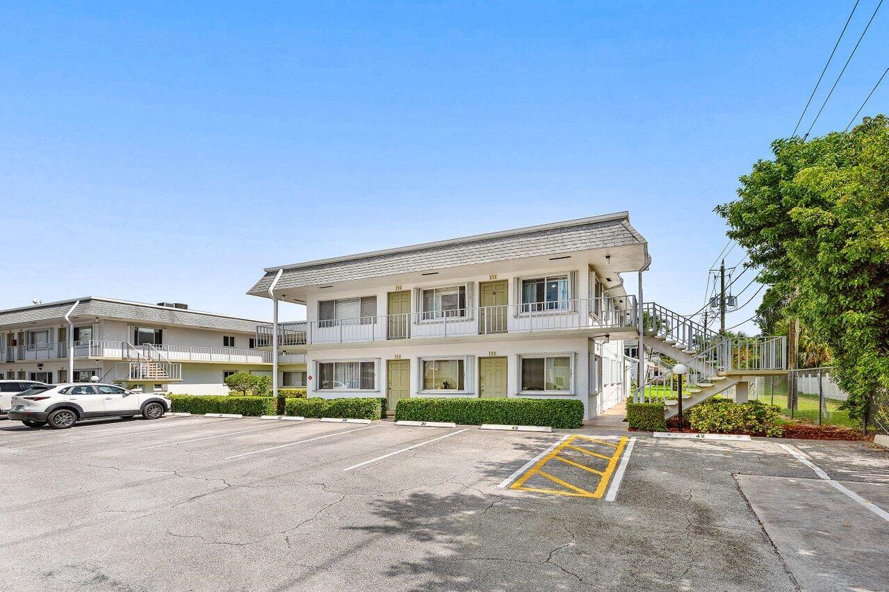 A two-story apartment building with exterior staircases and a parking lot in the foreground — 3280 Cynthia Lane # 214, FL 33461, FL