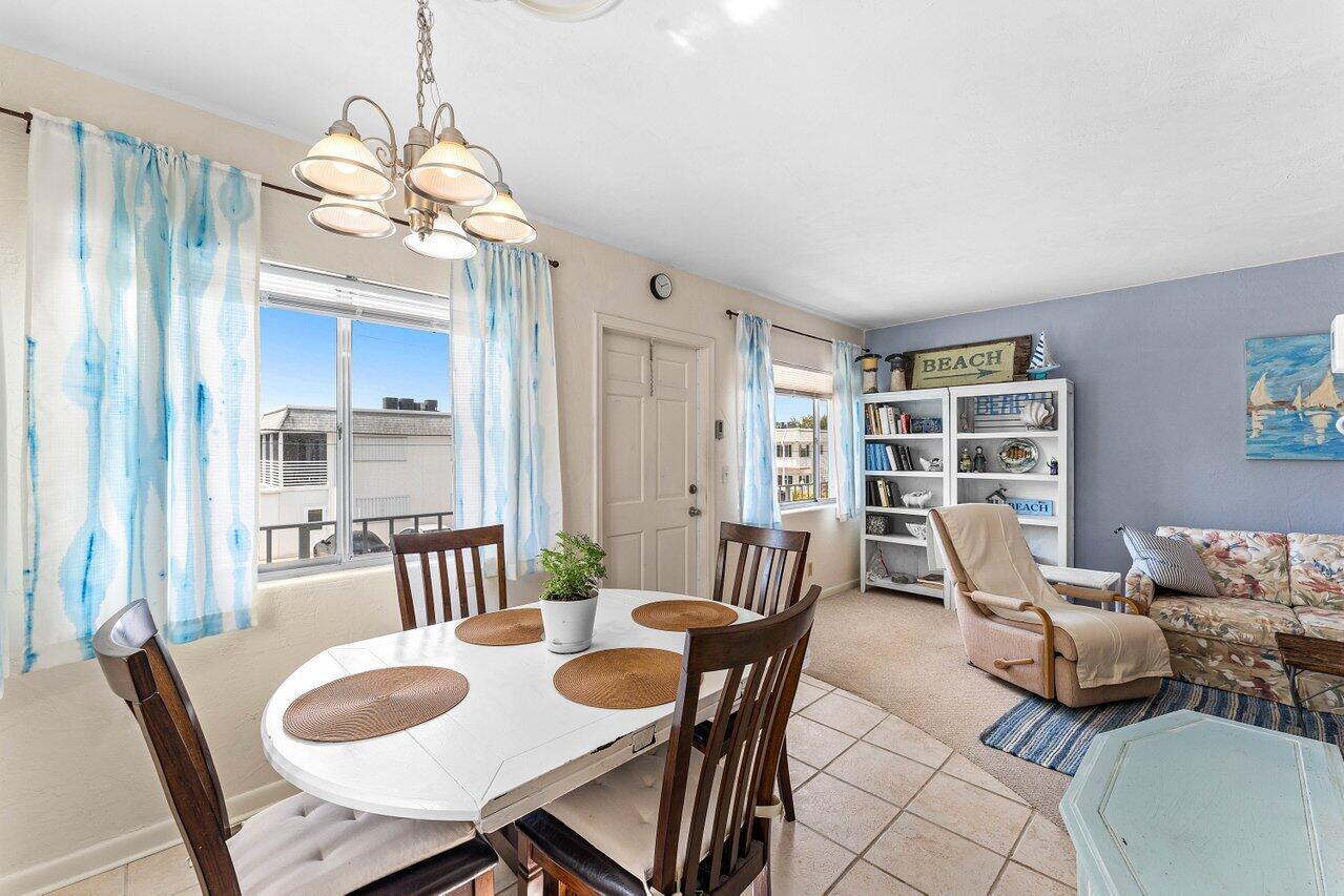 A dining area with a white table and chairs sits next to a living room — 3280 Cynthia Lane # 214, FL 33461, FL