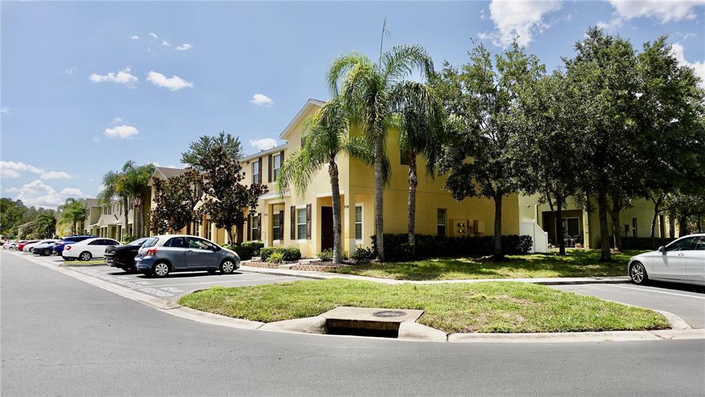 A yellow two-story townhouse complex features palm trees, green landscaping, and a paved parking lot — 8548 GABLEBEND WAY, TAMPA, FL