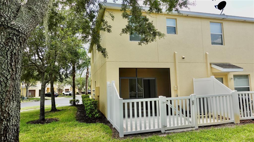 The exterior of a yellow two-story townhouse features a screened patio and white vinyl fencing — 8548 GABLEBEND WAY, TAMPA, FL